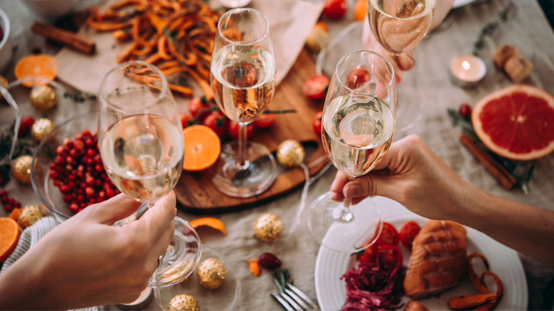 Toasting with champagne glasses at a festive holiday dinner table, featuring fruits and appetizers.