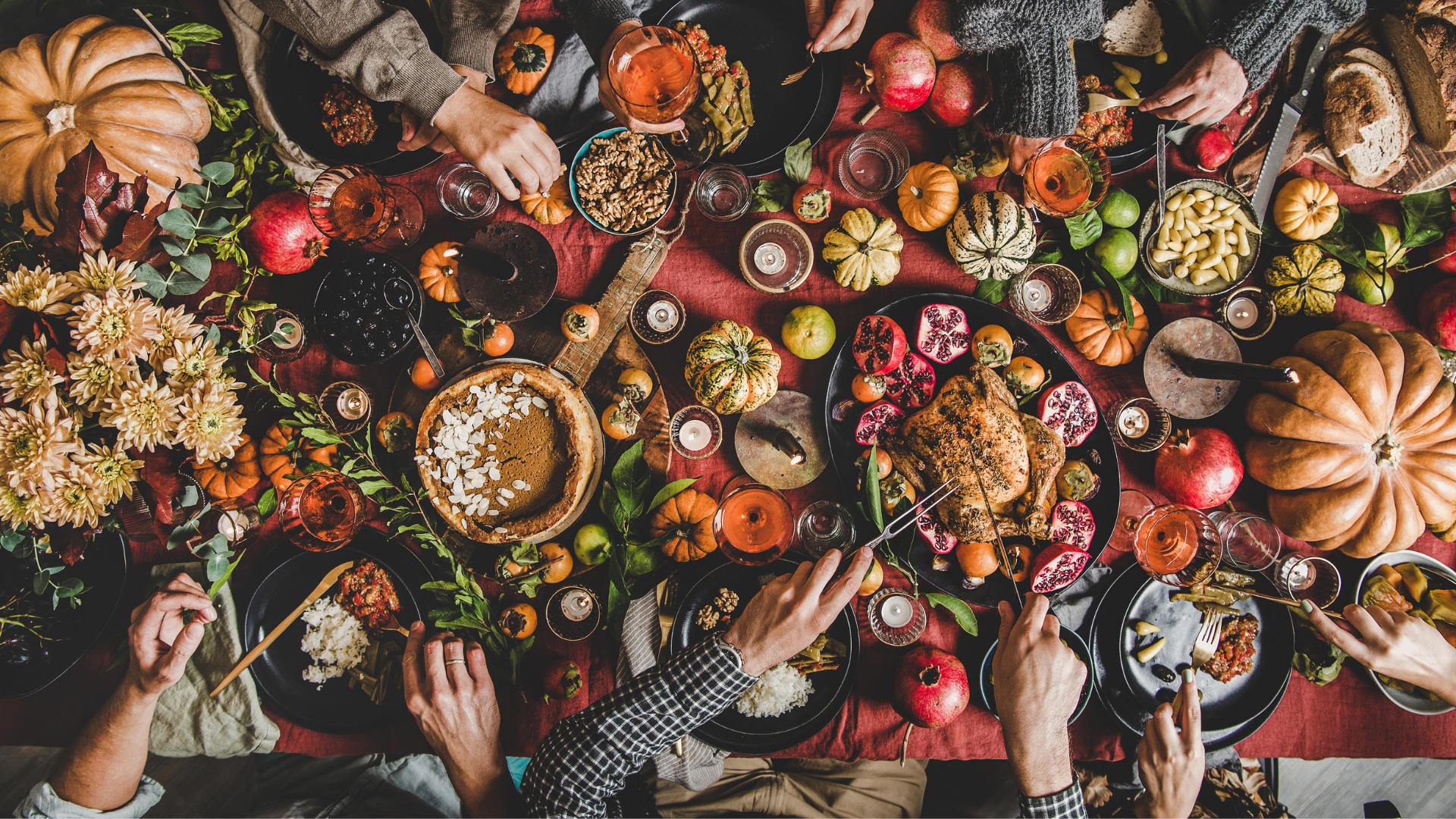 Thanksgiving feast with turkey, pie, pumpkins, and fruits on an autumn-themed table setting, top view.